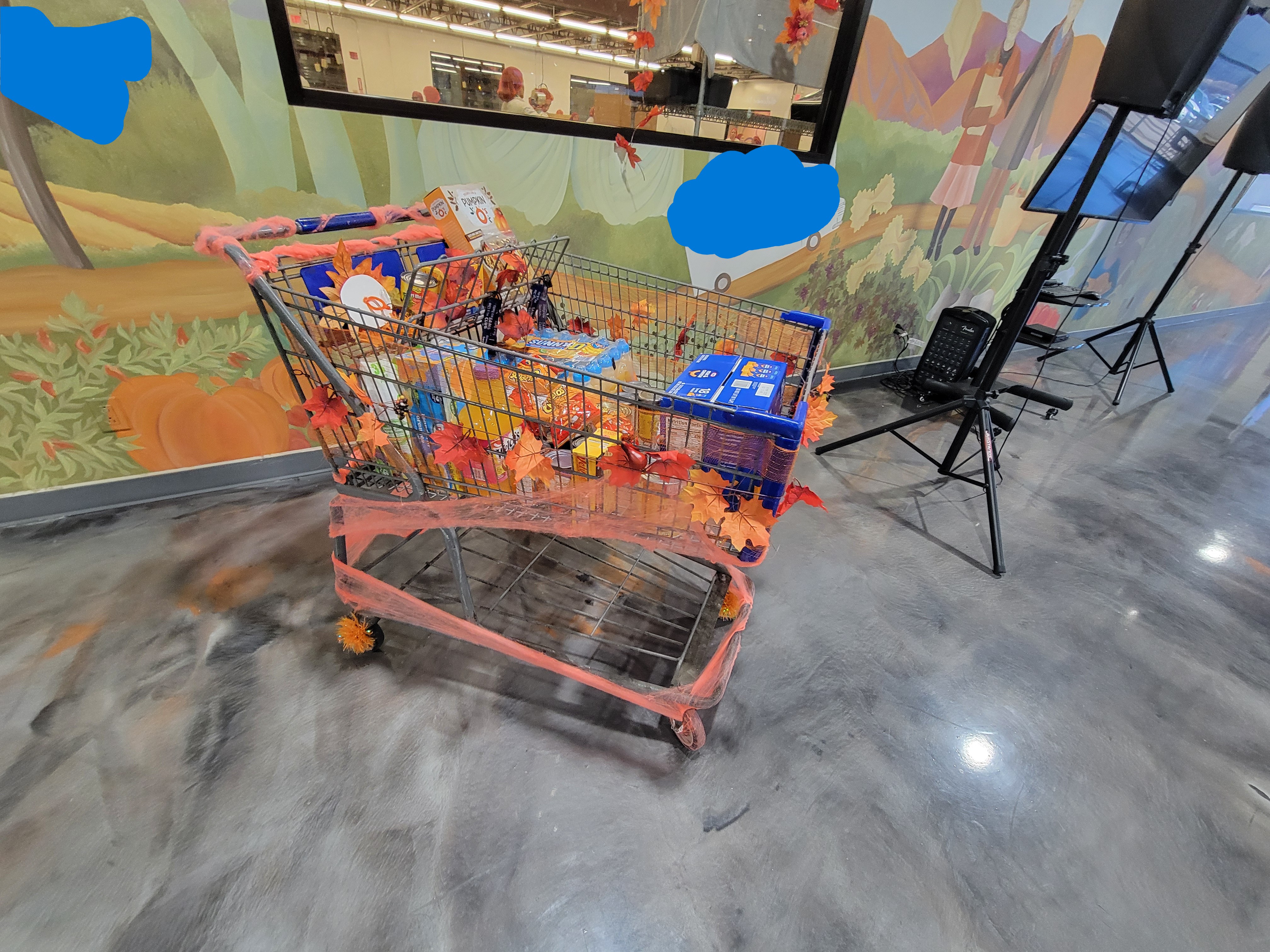 Side view of big shopping cart decorated with autumn decoration full of orange-ish foods.